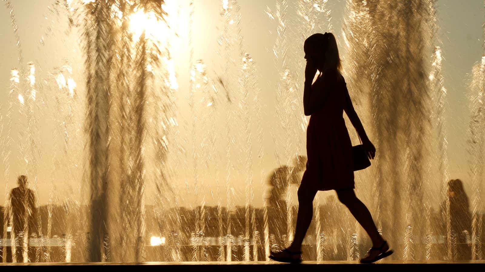 A woman is silhouetted in front of a fountain during sunset in Samara, Russia July 18, 2017.