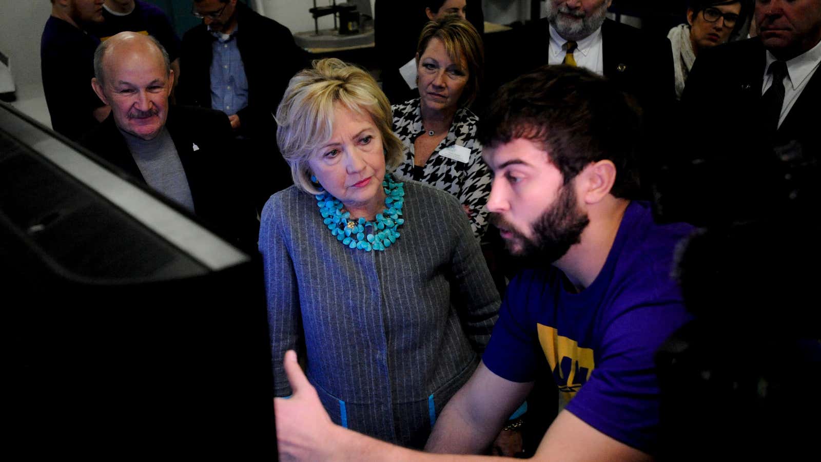 U.S. Democratic presidential candidate Hillary Clinton (C) is shown the designs that are fed into the 3-D printer at Cedar Valley TechWorks in Waterloo, Iowa…