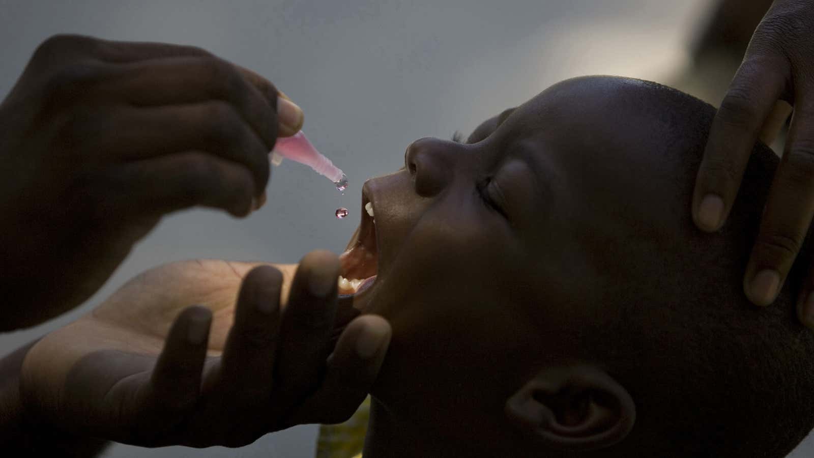 A health official gives drops of oral polio vaccination to a child at the Mission of Mercy school in the Cite Soleil slum, in Port-au-Prince,…