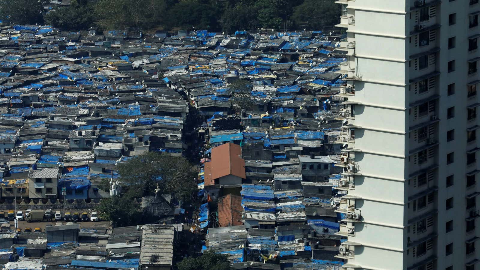 A high rise residential building is seen next to a slum in Mumbai, India, December 20, 2017. – RC19141C98C0