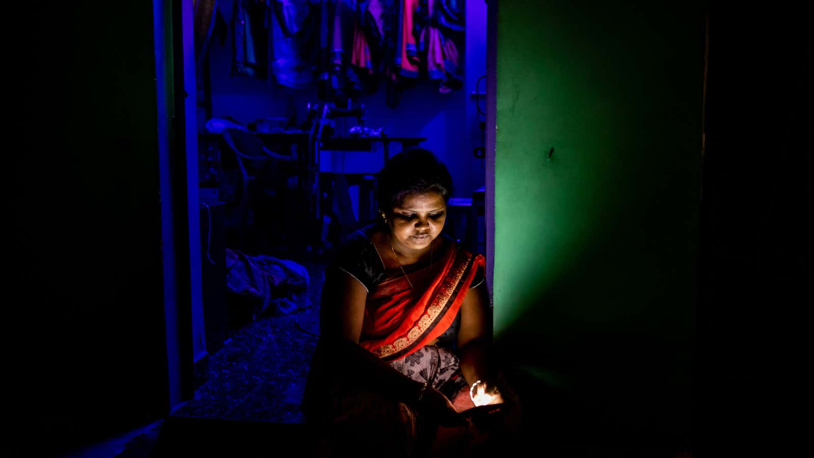 Sweety Devangan, a 42-year-old tailor, checks her phone during a power outage near a coal power plant in Korba, Chhattisgarh.
