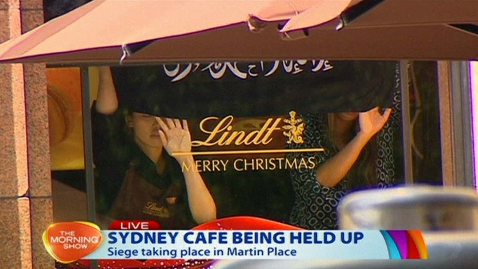 People holding up what appeared to be a black flag with white Arabic writing on it, inside a cafe in Sydney, Australia.