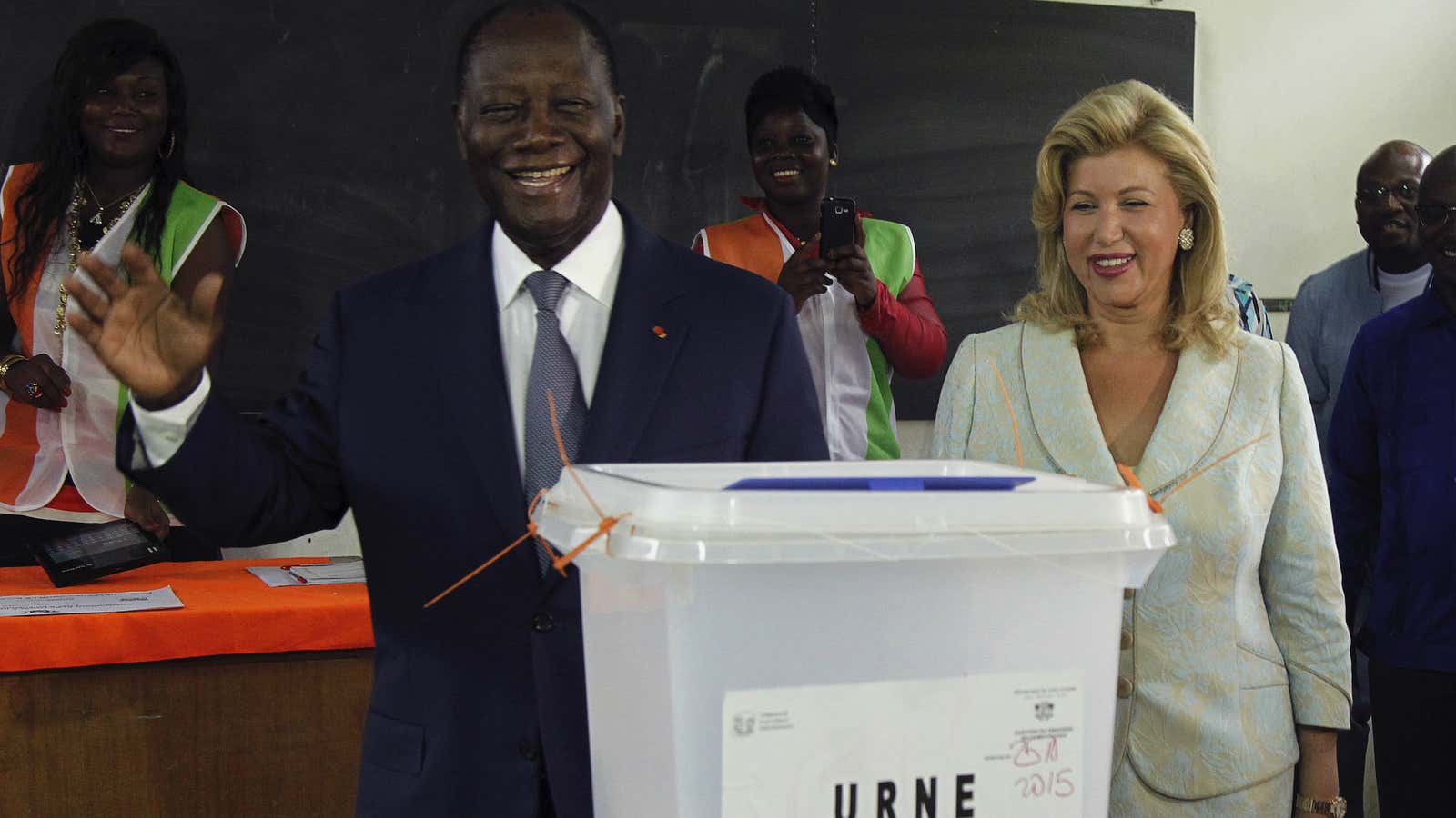 Ivorian president Alassane Ouattara stands next to his wife as he casts his ballot.
