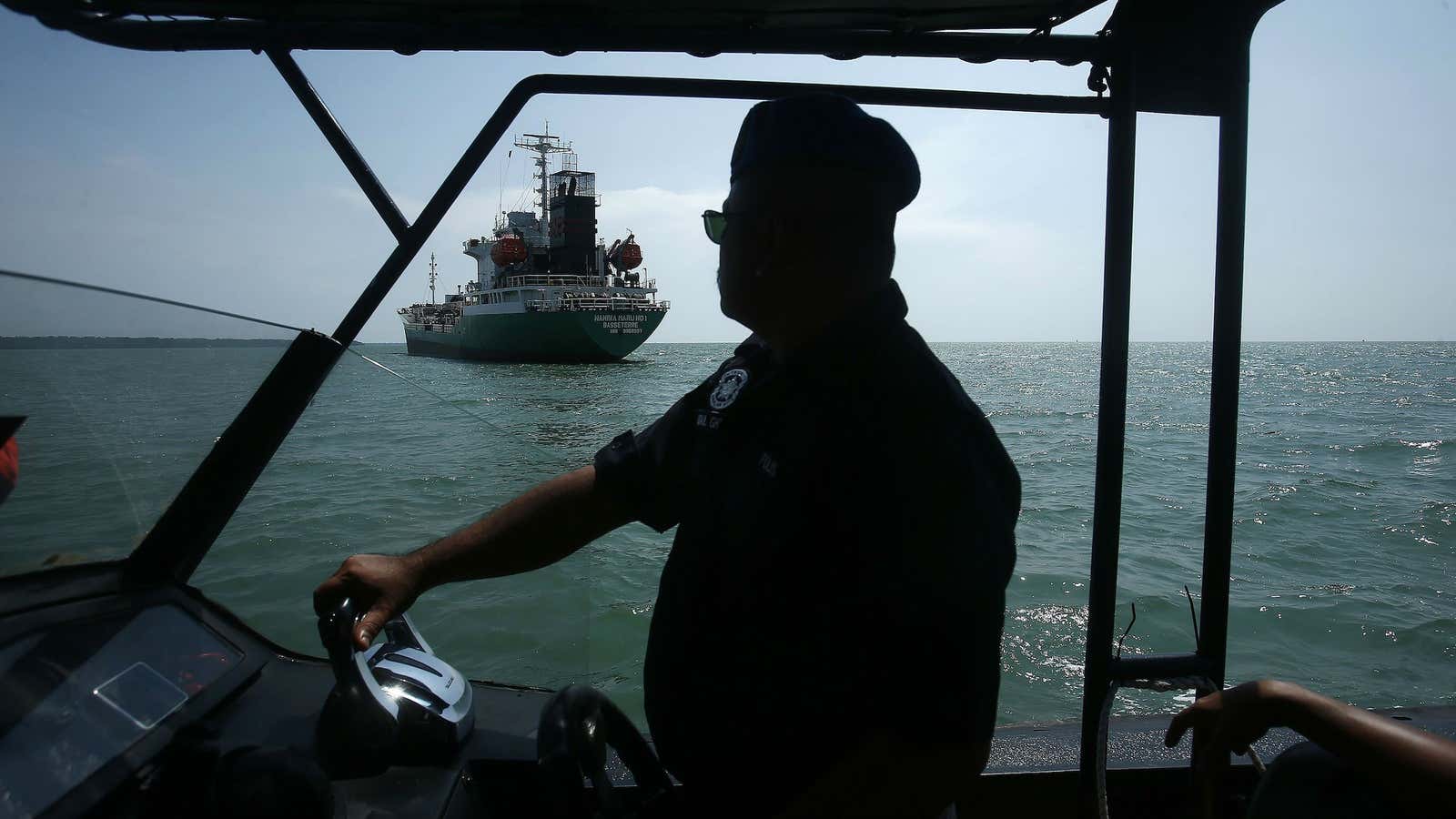 Maritime police approach an oil tanker that was raided by pirates off the coast of Malaysia.