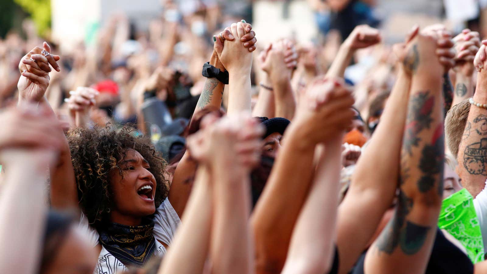 Protestors clasp hands in solidarity at a protest against racial inequality.