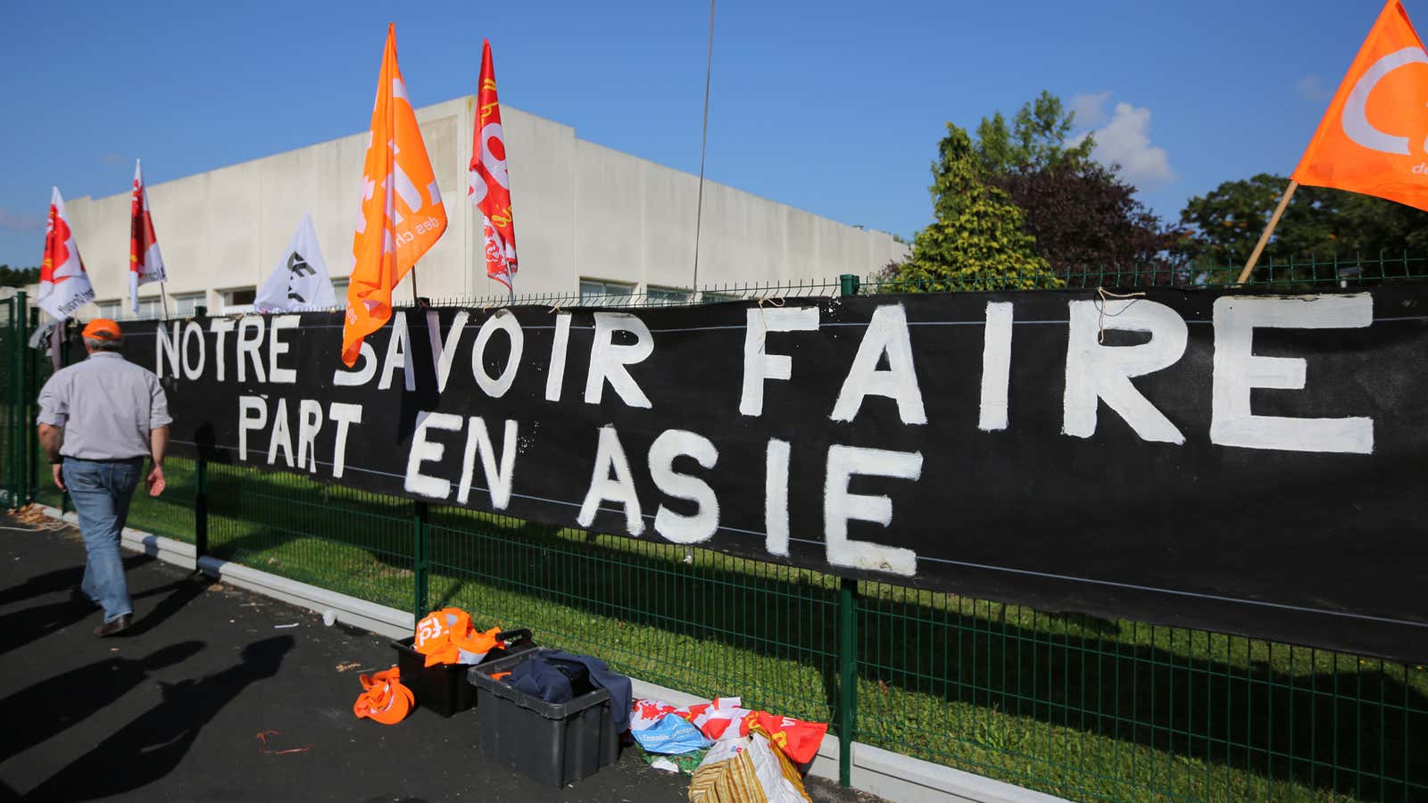 A banner in protest of layoffs at Alcatel-Lucent reads, “Our know-how goes to Asia.”