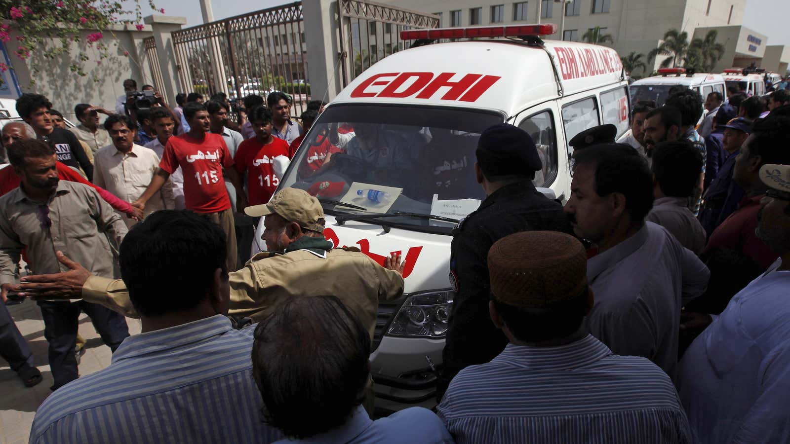 People gather as rescue workers and volunteers makes way for ambulances, carrying bodies of the victims of an attack on a bus, as they move outside the hospital in Karachi, Pakistan, May 13, 2015
