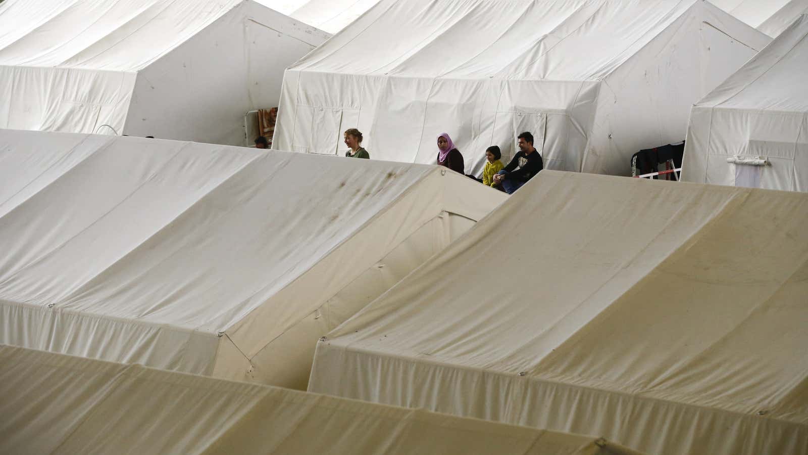 People gather among tents at a shelter for migrants inside a hangar of the former Tempelhof airport in Berlin.