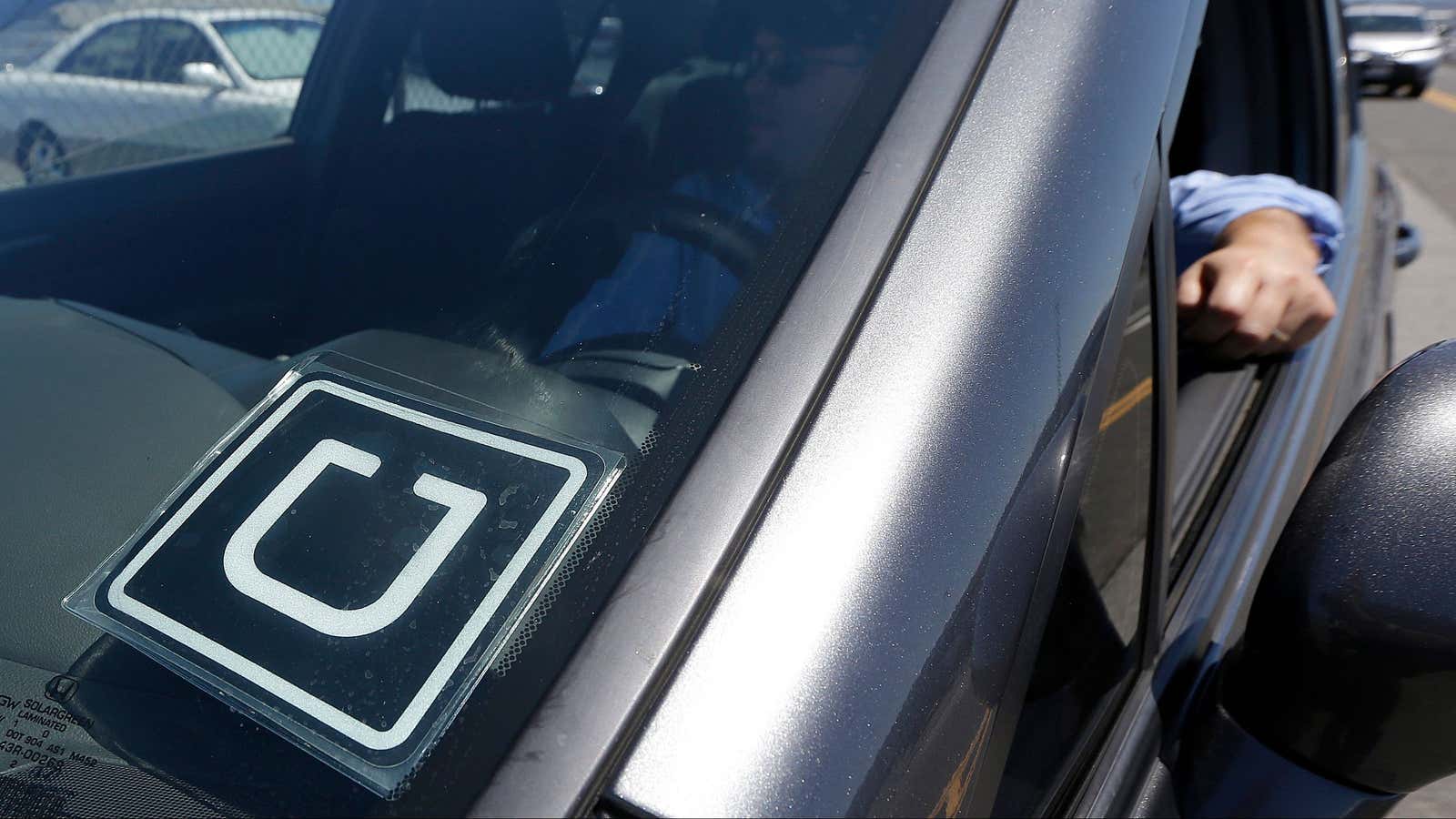 FILE – In this July 15, 2015, file photo, Uber driver Karim Amrani sits in his car parked near the San Francisco International Airport parking…