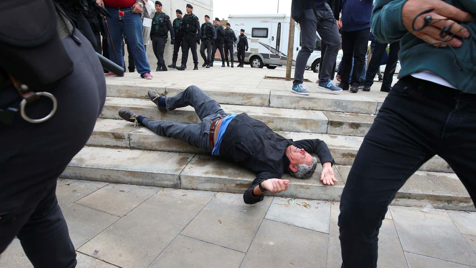 A man falls to the ground during scuffles with Spanish police.