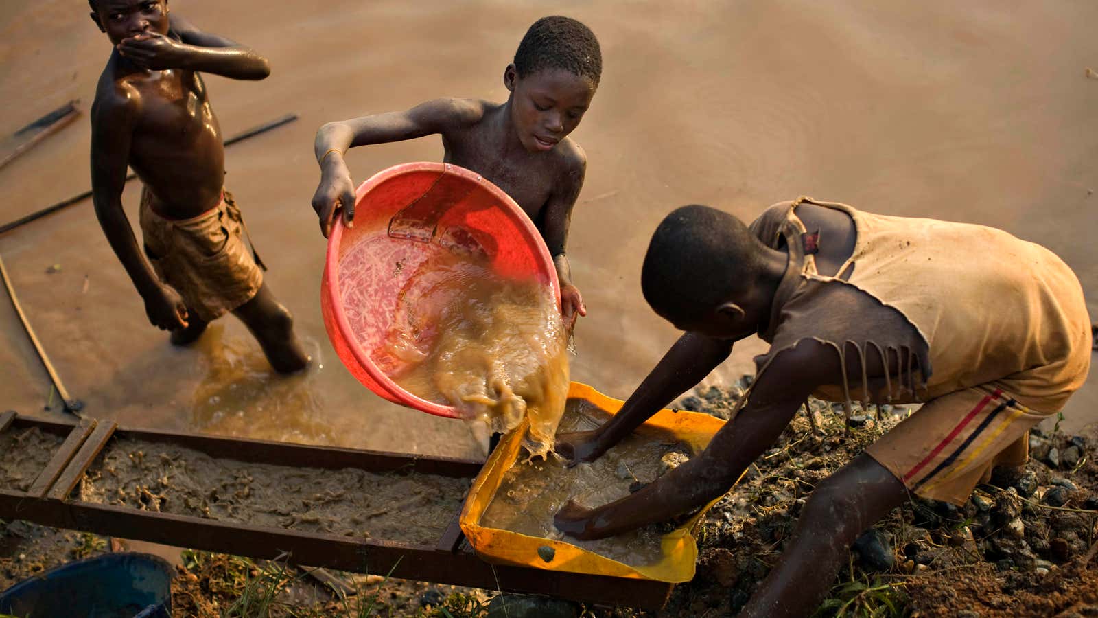 Boys pan for gold on a riverside at Iga Barriere in eastern Congo.