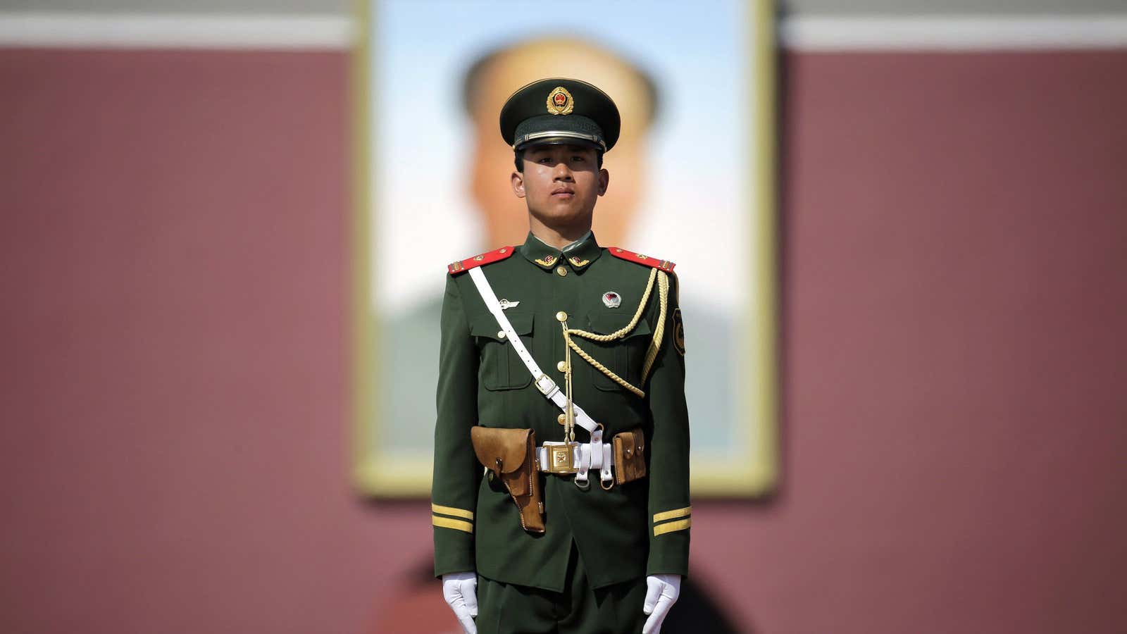 A paramilitary police officer stands guard in front of a portrait of China’s former chairman Mao Zedong.