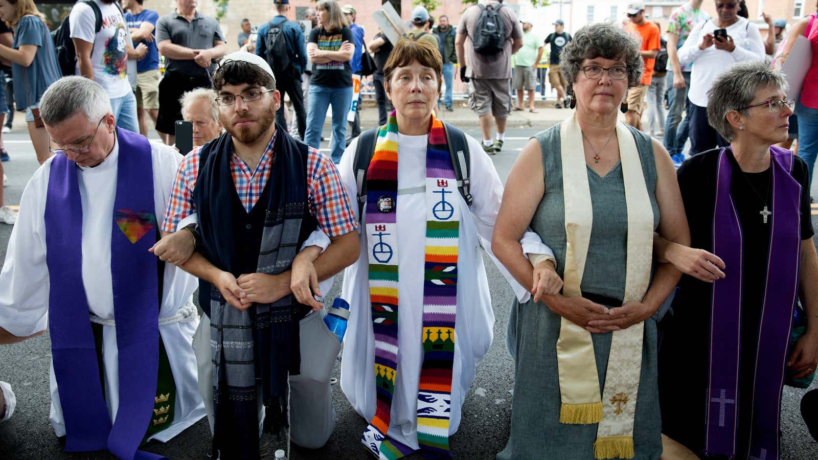 Local clergy leaders link arms at a counter-protest in Charlottesville on Saturday, Aug. 12.