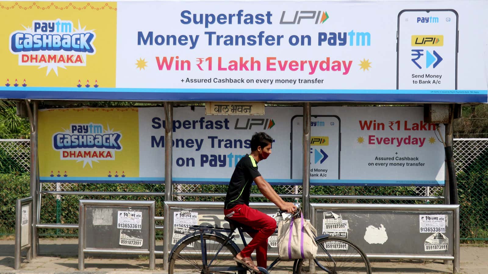 A man rides a bicycle past a bus stop with Paytm advertisements in Mumbai, India, November 10, 2021.