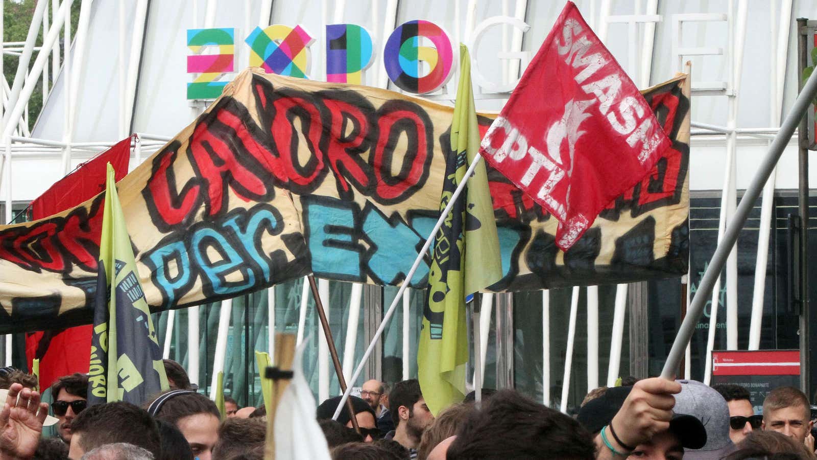 Protesters wave a banner reading in Italian, ‘We do not work for free Expo’,