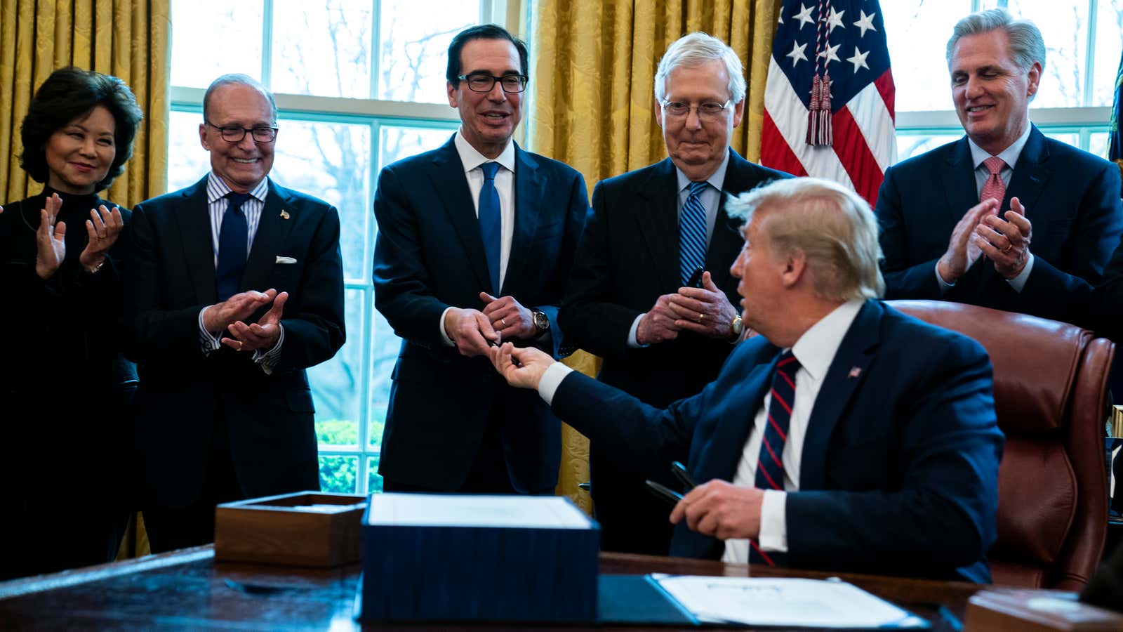 Trump signing the first stimulus bill in March.