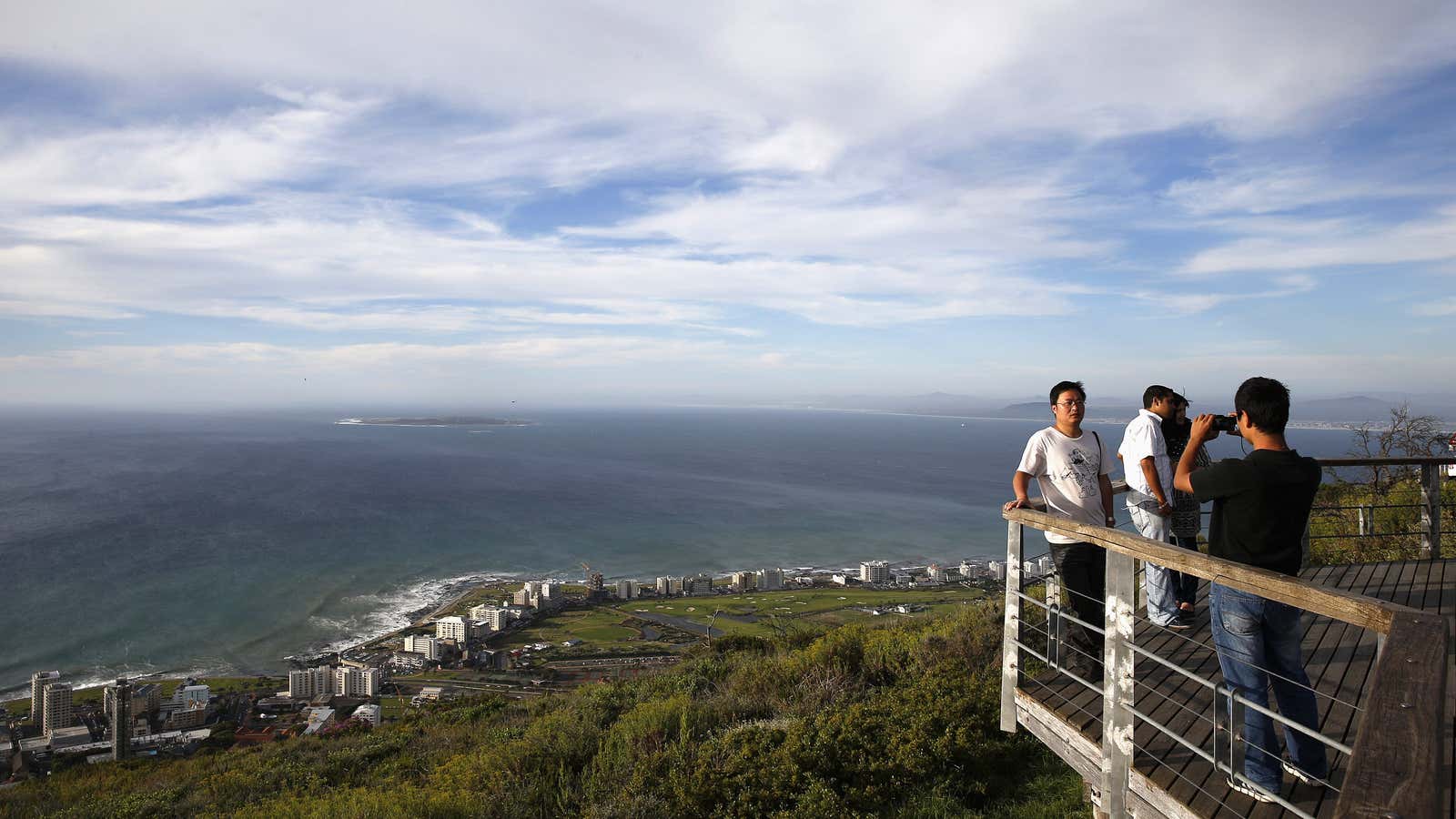 Tourists take pictures  overlooking Cape Town’s Atlantic beachfront and Robben Island,
