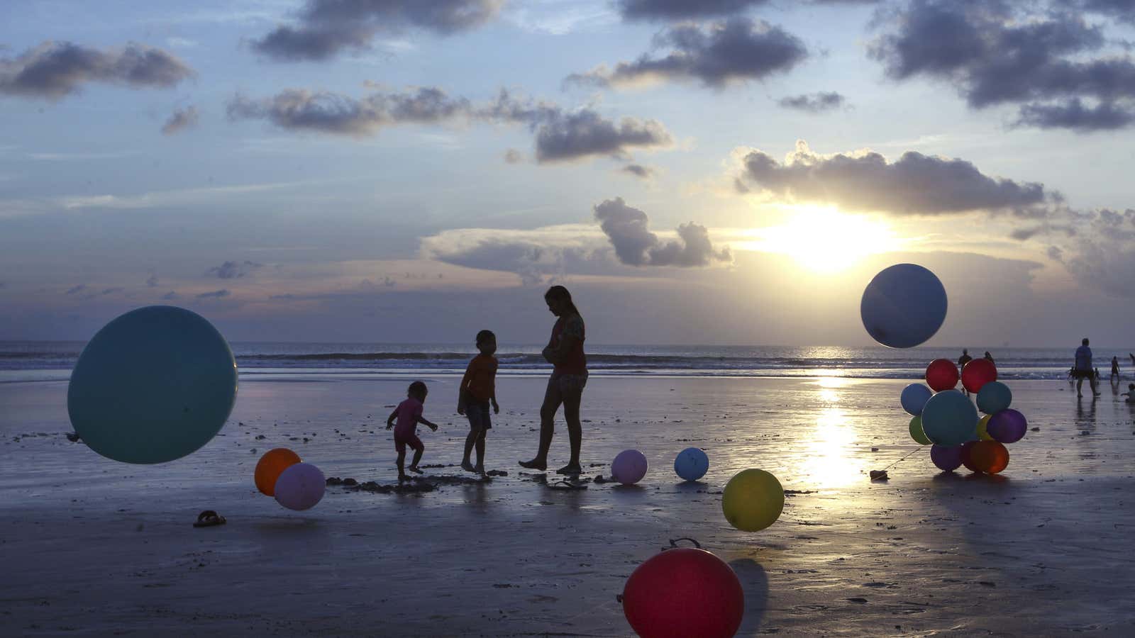 A mother plays with her children on the beach during sunset in Bali, Indonesia, Saturday, April 29, 2017. (AP Photo/Firdia Lisnawati)