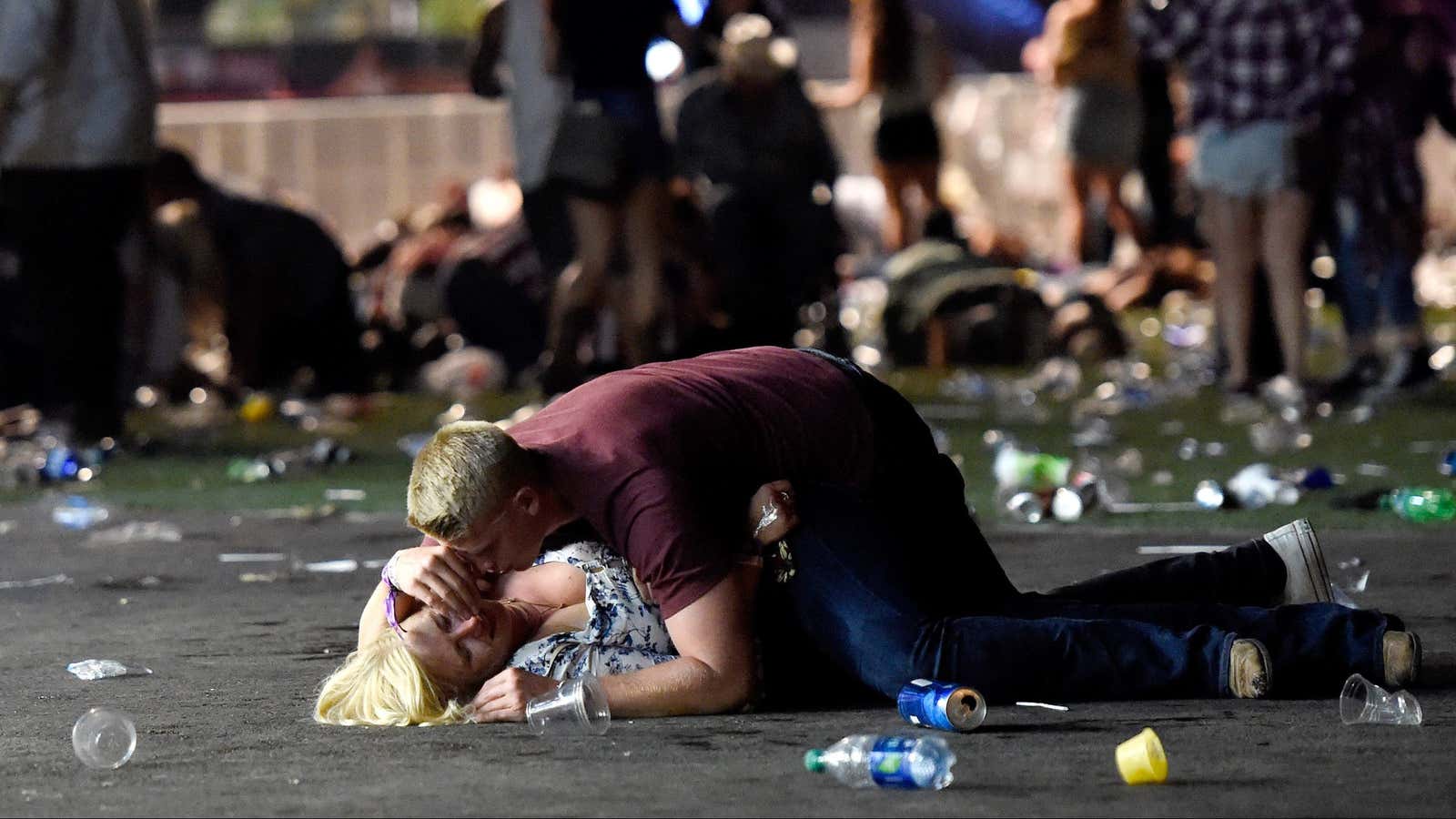 A man lays on top of a woman as others flee the Route 91 Harvest country music festival grounds after a active shooter.