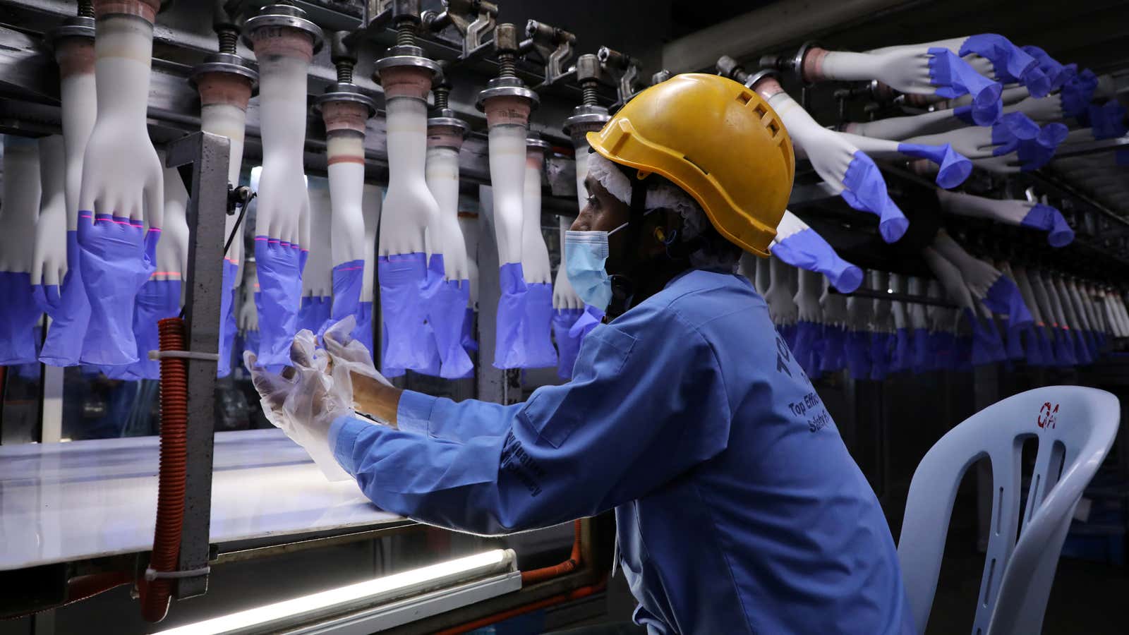 A worker inspects newly-made gloves at Top Glove factory in Shah Alam, Malaysia August 26, 2020. REUTERS/Lim Huey Teng