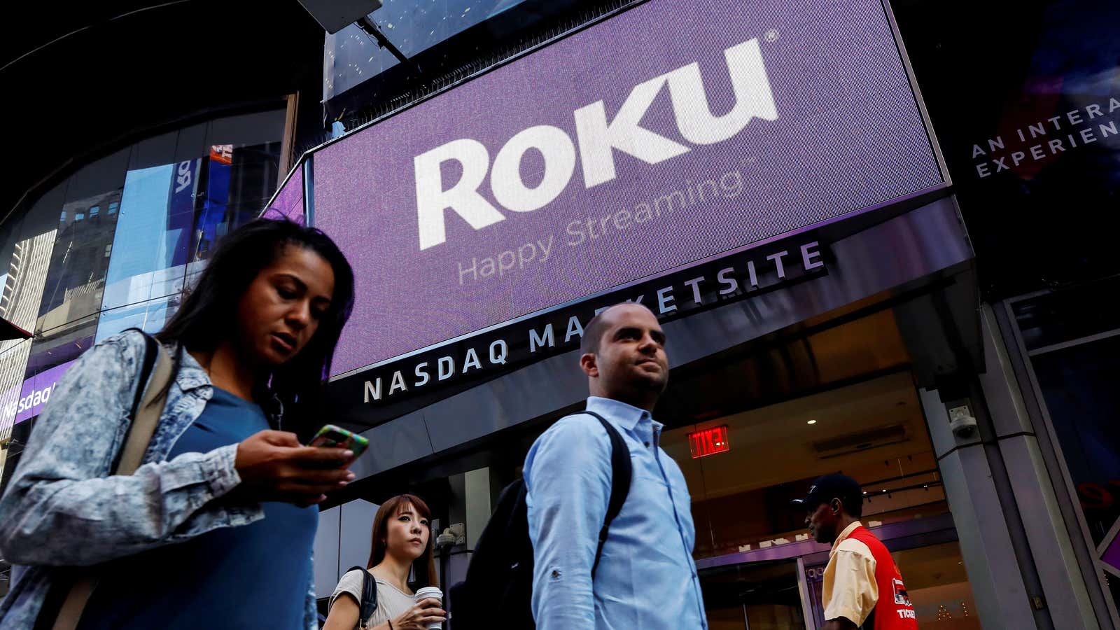 People pass the Roku logo in New York City.
