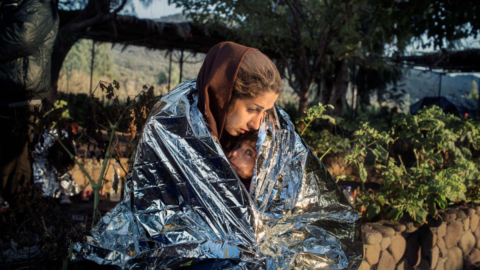 A mother and child  wrapped in an emergency blanket after disembarking on the beach of Kayia, on the north of the Greek island of Lesvos.