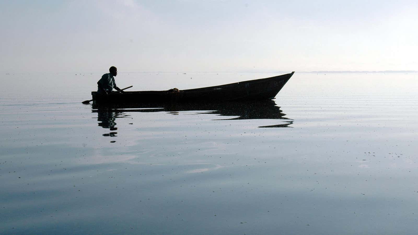 A Ugandan fisherman rows back to his nets at dawn on Lake Victoria,.