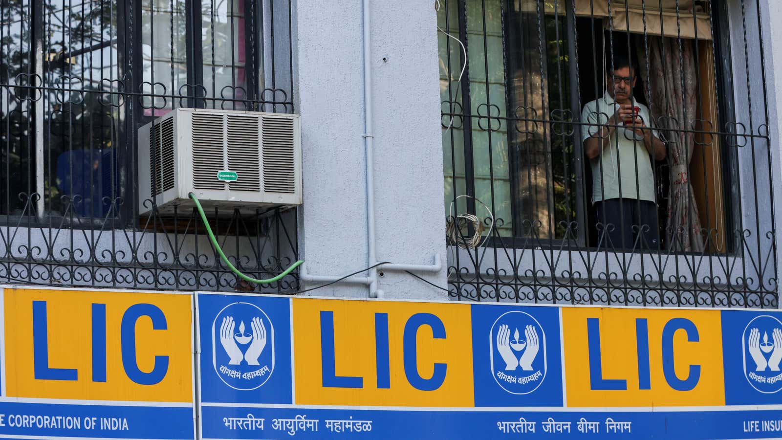 A man looks out of the window of a house above the Life Insurance Corporation of India (LIC) office in Mumbai, India January 28, 2022.