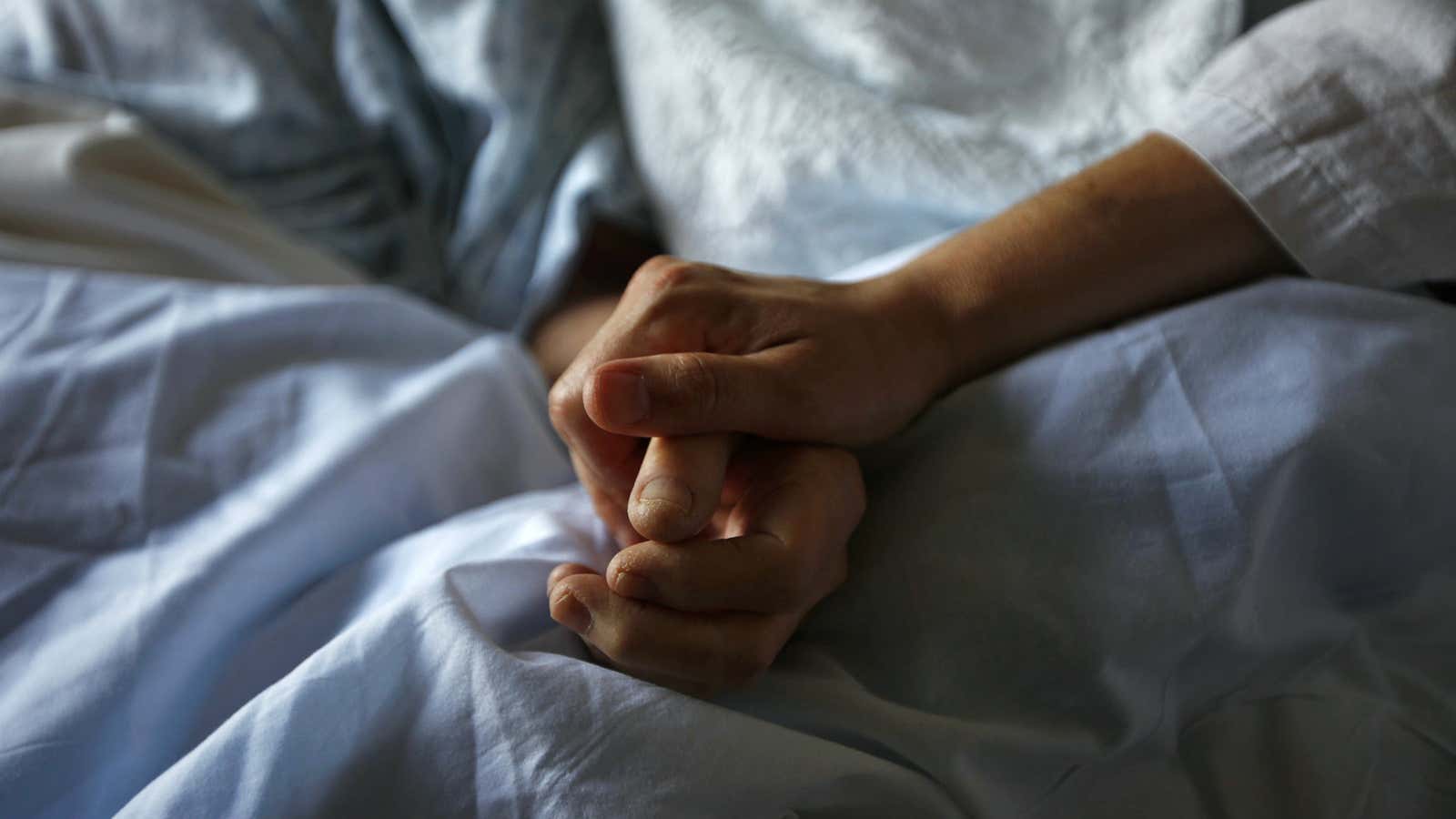 HEADLINE:A woman holds the hand of her mother who is dying from cancer during her final hours at a palliative…