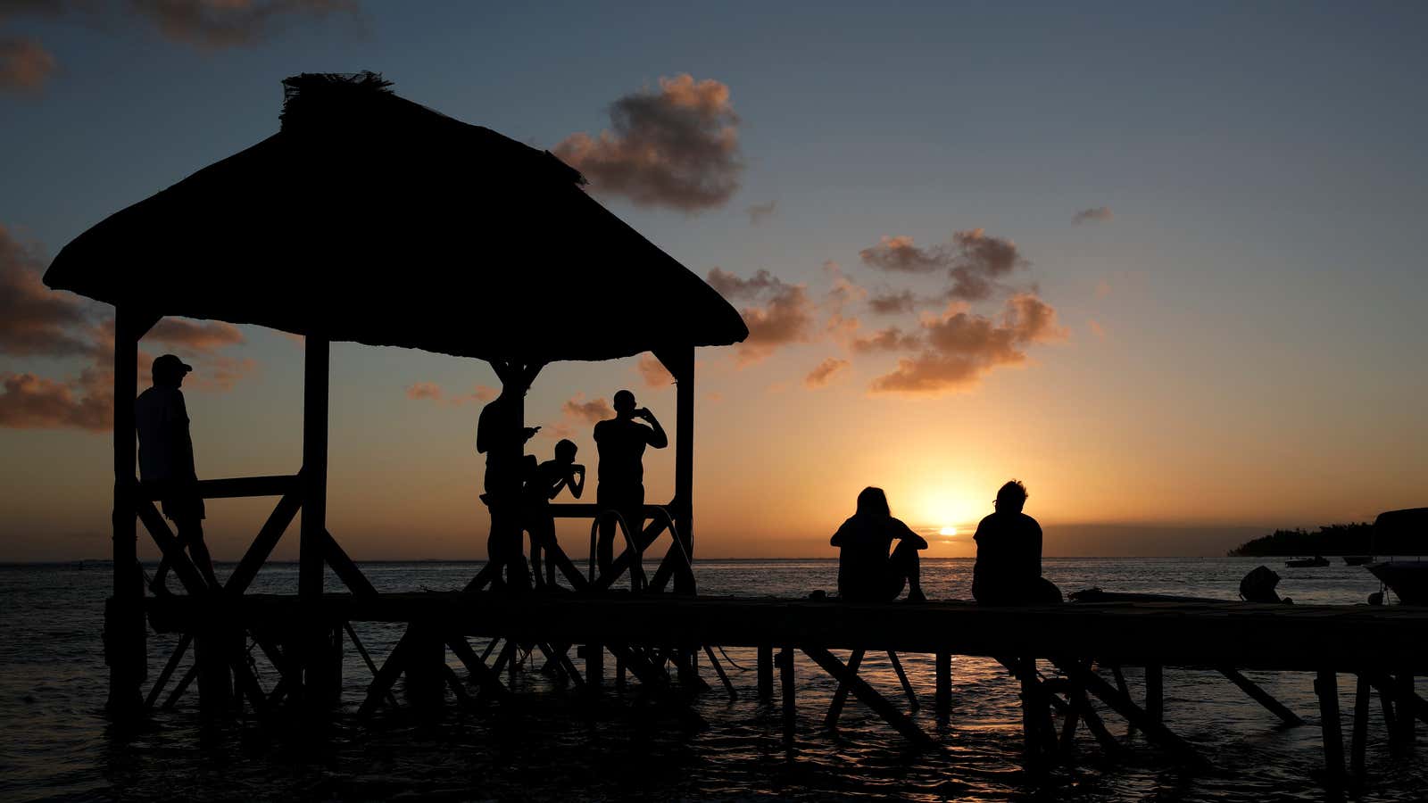 People watch as the sunset in Mauritius drops as low as its tax rates.