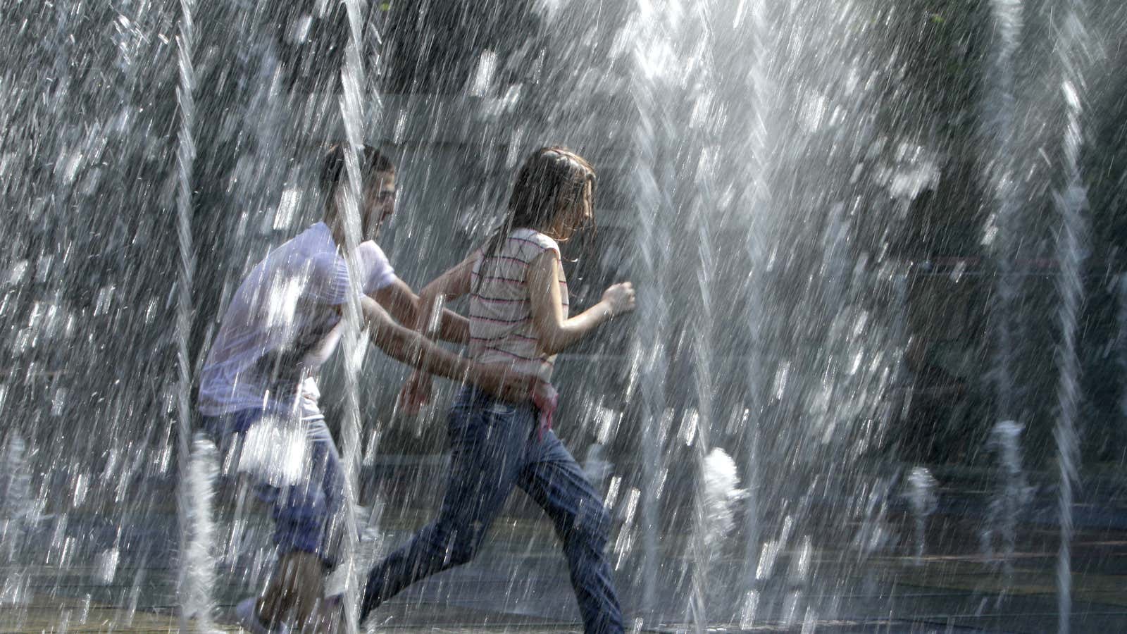 Youths play at a fountain during a hot summer day in Tbilisi