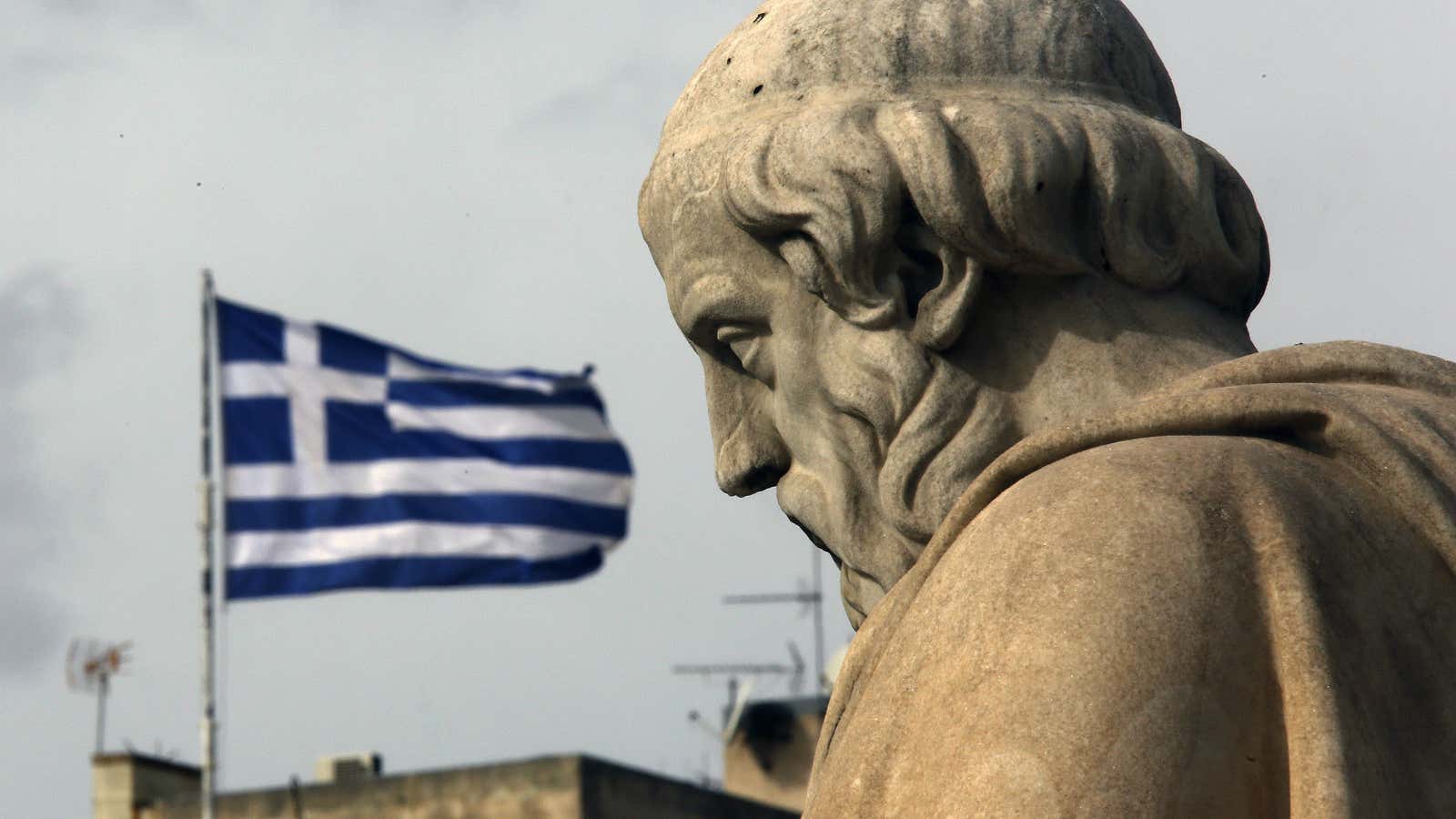 A Greek flag flutters above the statue of Greek philosopher Plato outside the Athens Academy, February 2, 2015. Greece’s new left-wing government will not take…