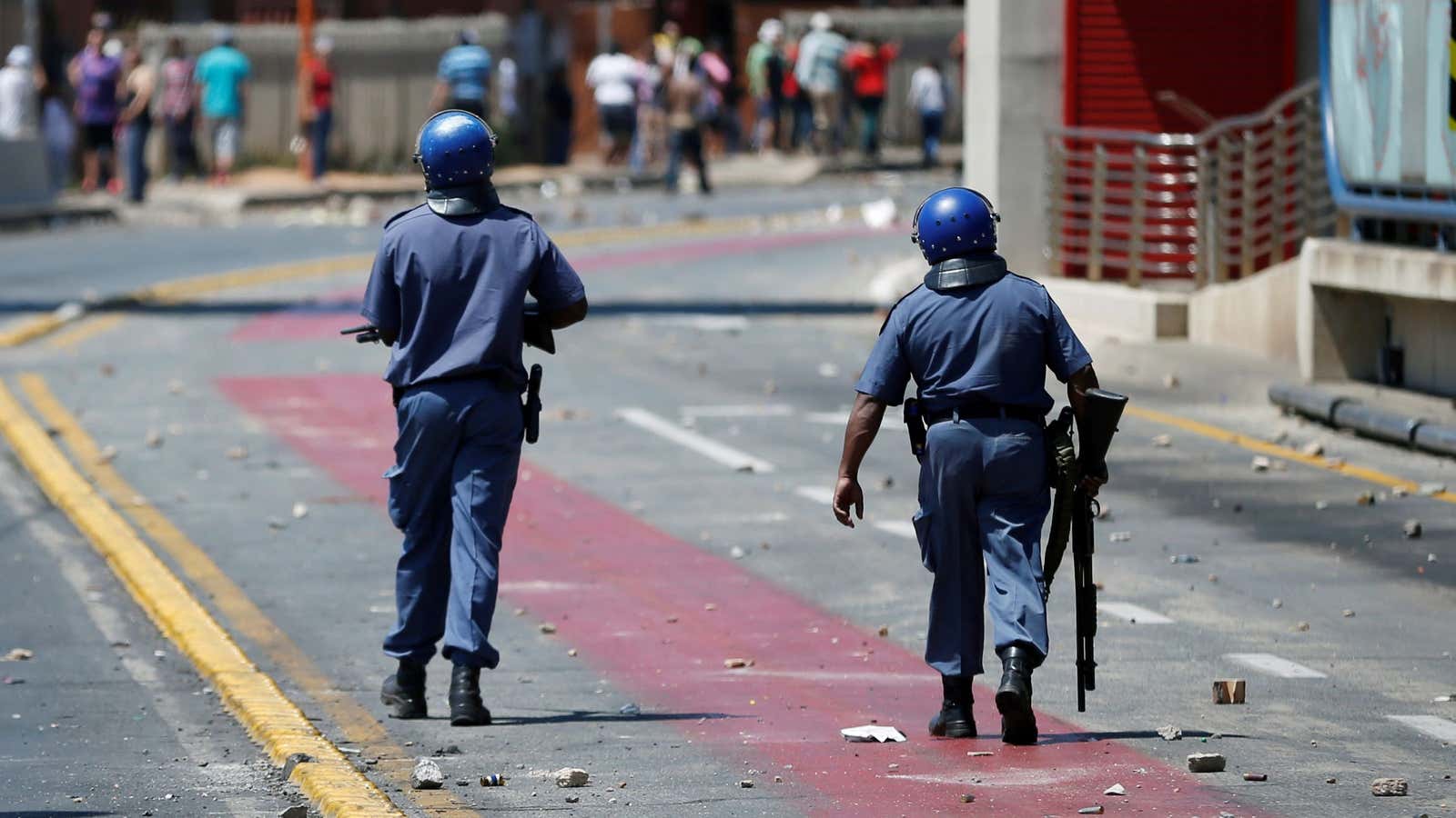 Police patrol down a rock strewn road during clashes with protesters in Johannesburg, South Africa, October 1, 2018.