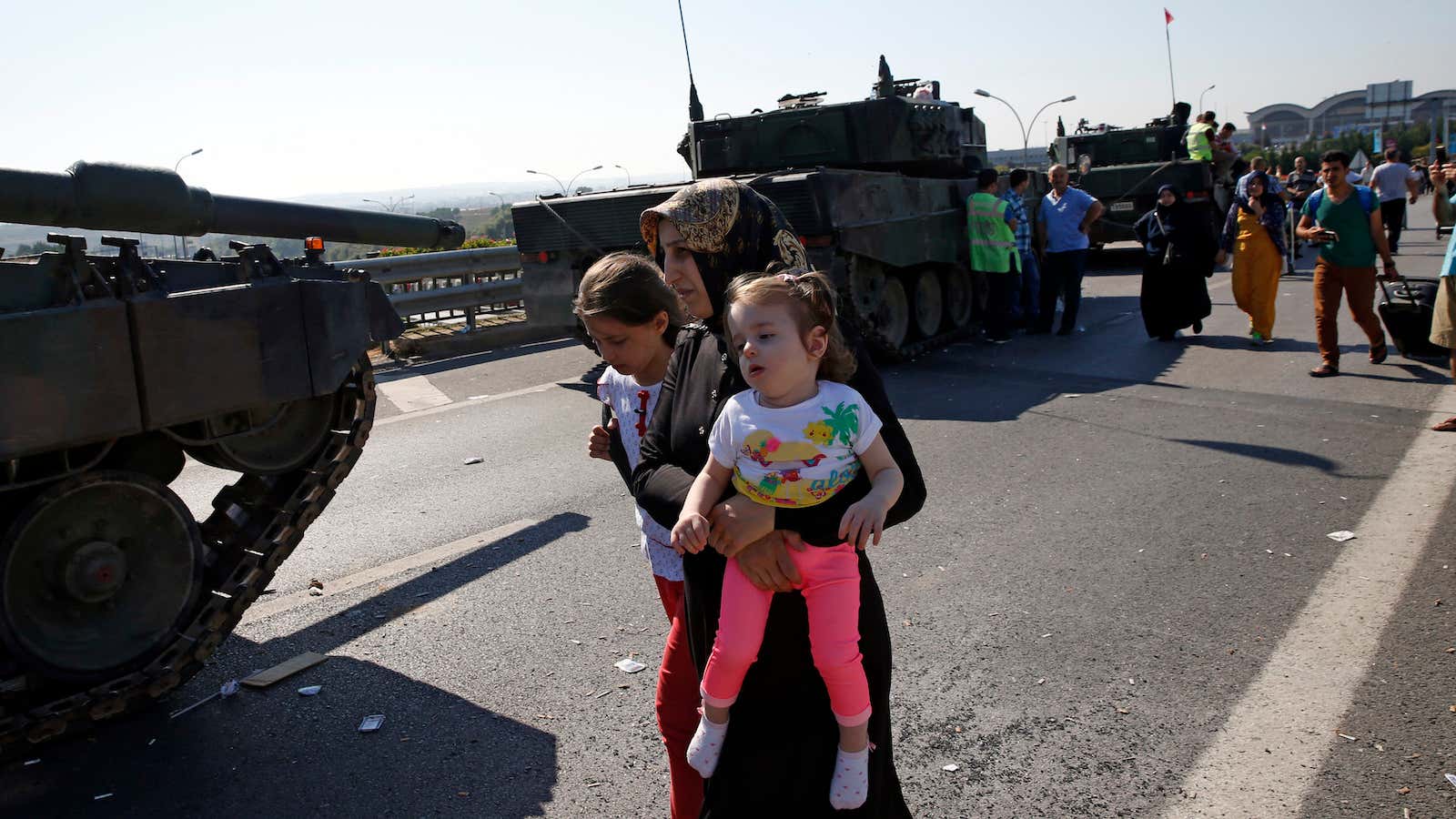 A woman with two girls walks past military vehicles in Istanbul the day after the attempted coup.