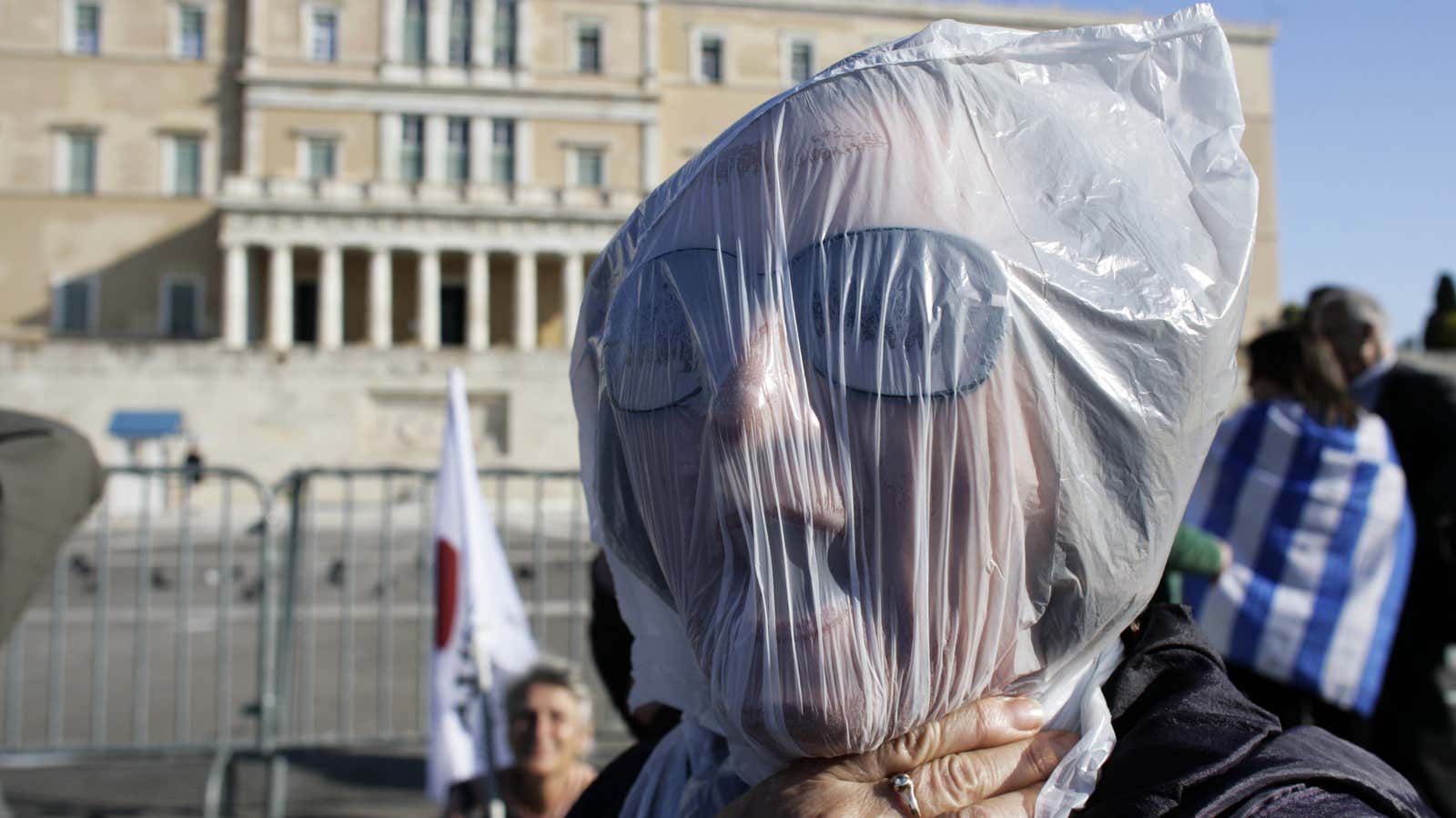 A Greek woman protests austerity measures earlier this month. Despite today’s deal, Greece is left holding the bag on a huge debt burden.
