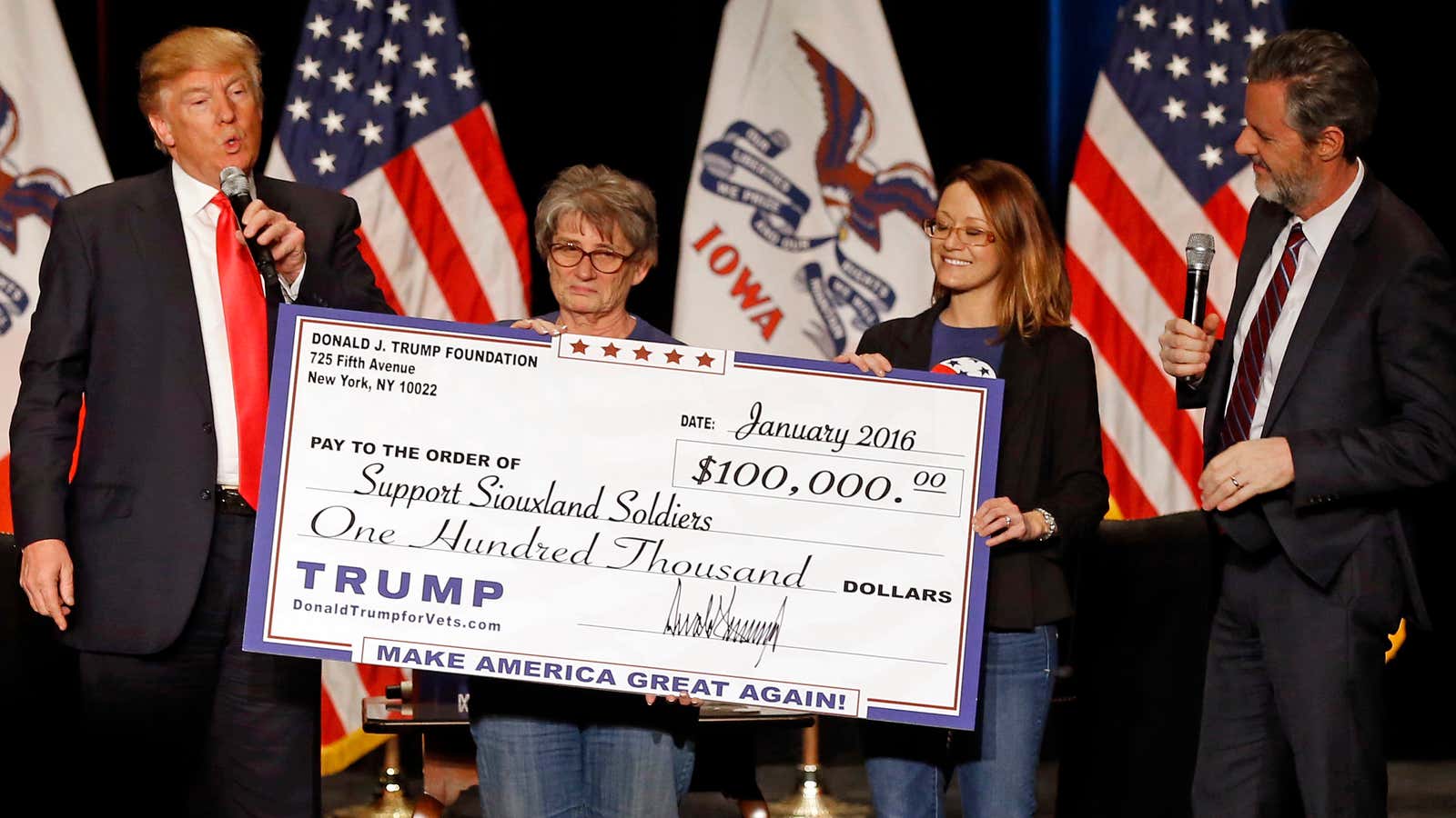Donald Trump presents a check in Iowa the day before the 2016 Republican primary caucus there.