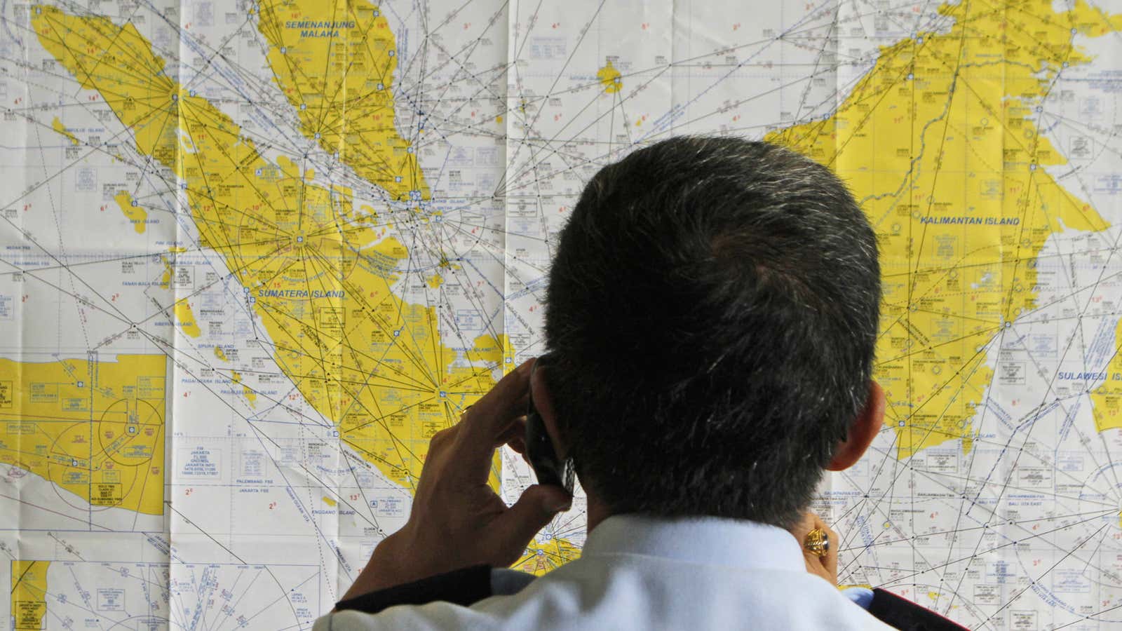 An airport official checks a map of Indonesia at the crisis center set up by local authority for the missing AirAsia flight QZ8501, at Juanda International Airport in Surabaya, East Java, Indonesia.