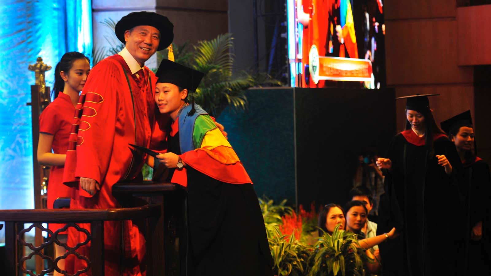 Draped in a rainbow flag, Wan Qing hugs the university president at her graduation ceremony.