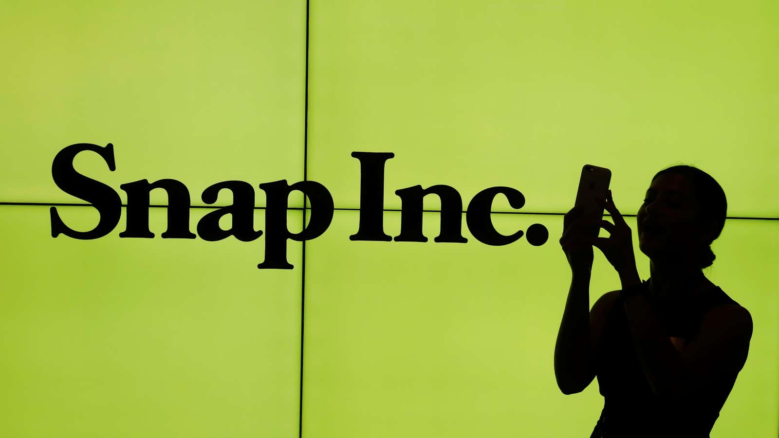 A woman stands in front of the logo of Snap Inc. on the floor of the New York Stock Exchange (NYSE) while waiting for Snap…