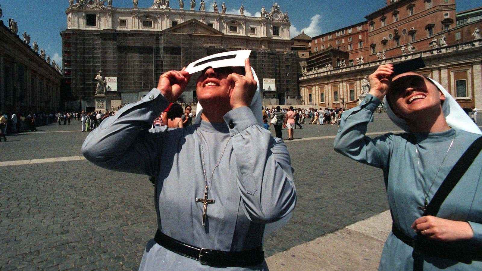 Two unidentified nuns watch a solar eclipse through protective glassed outside of St. Peter’s Square at the Vatican, on Aug. 11, 1999.