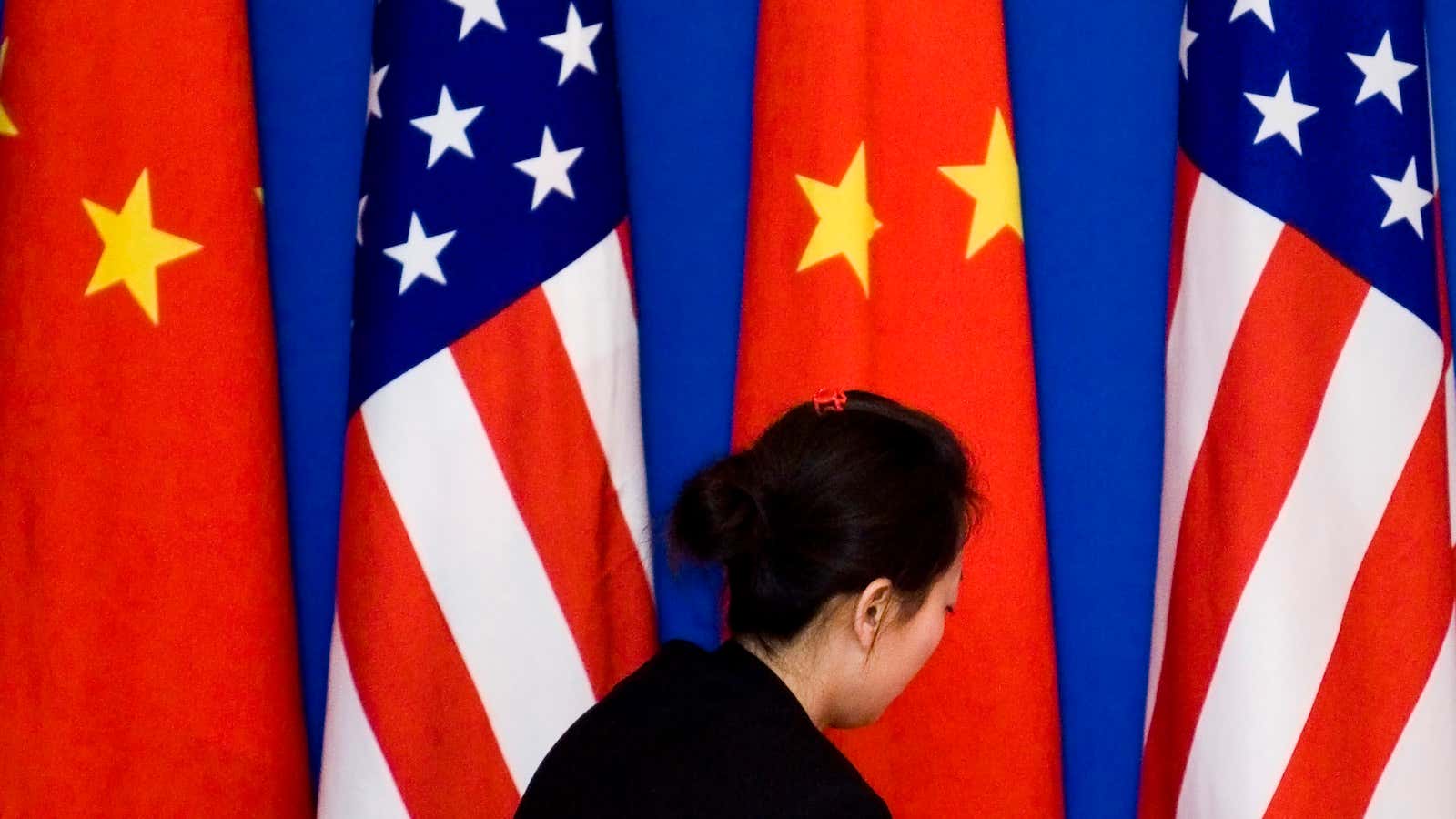 A Chinese woman arranges the Chinese and U.S. flags on stage before both countries’ delegates group photo session for Third China-US Strategic Economic Dialogue at…