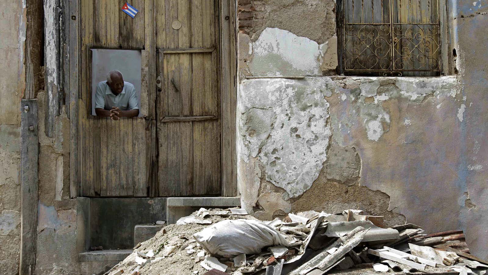 A man looks out from the window of his home to survey damage from Hurricane Sandy in Santiago de Cuba, Cuba.