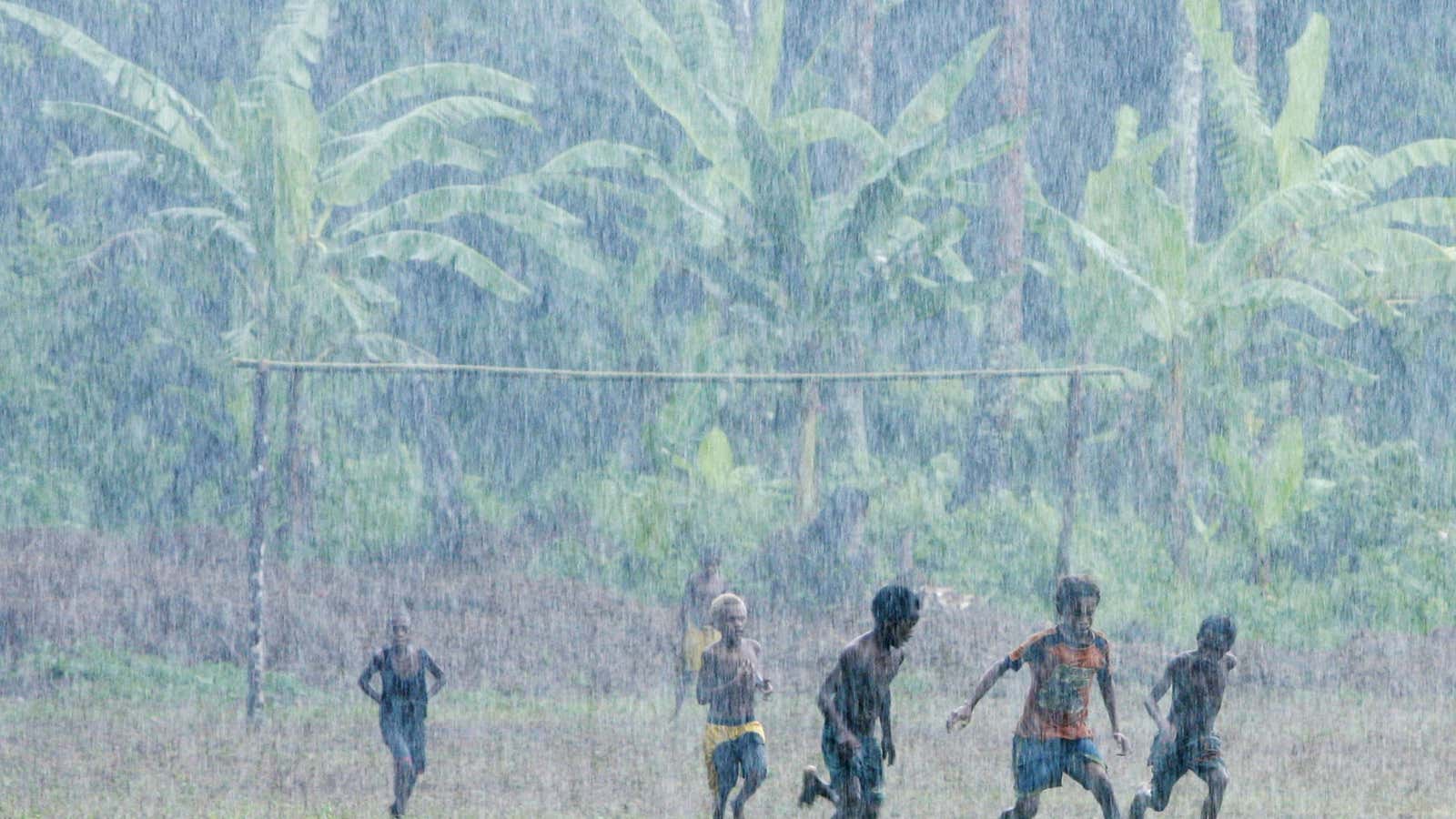 Displaced children from Lolovoli village on the island of Ambae, part of the Vanuatu islands chain, play soccer in torrential rain at their evacuee center,…