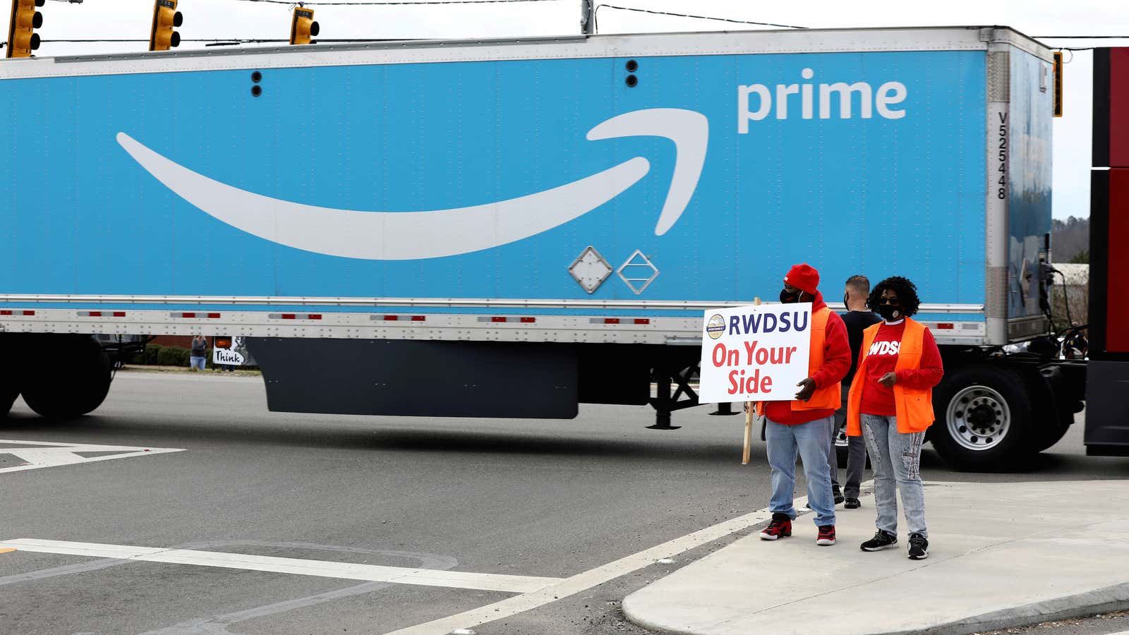 People hold a banner at the Amazon facility as members of a congressional delegation arrive to show their support for workers who will vote on…