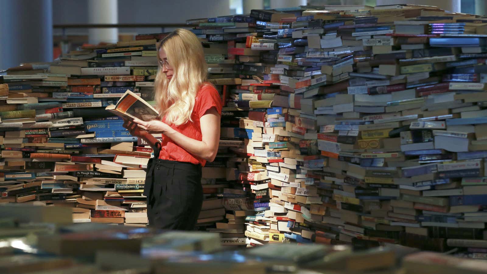 A gallery assistant poses with a book inside a labyrinth installation made up of 250,000 books titled “aMAZEme” by Marcos Saboya and Gualter Pupo at…