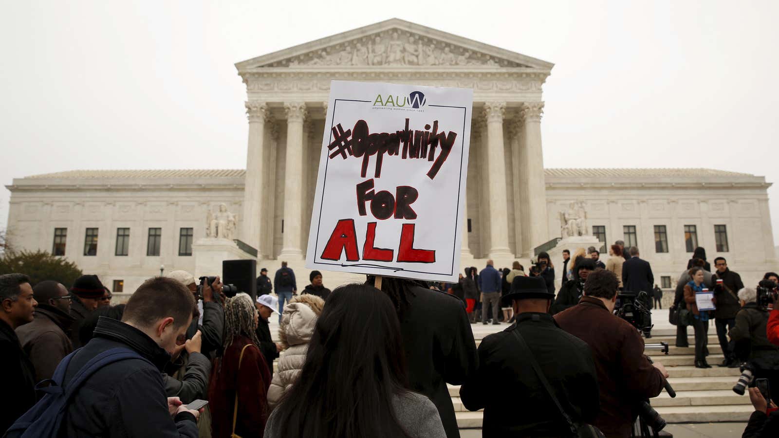 A demonstrator holds a sign aloft as the affirmative action in university admissions case was being heard at the Supreme Court in Washington, December 9, 2015. REUTERS/Kevin Lamarque  – RTX1XX96