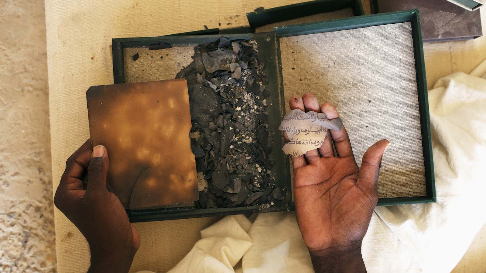Alkanis Cisse holds the remnants of a burned Islamic manuscript at the Ahmed Baba Centre for Islamic learning in Timbuktu July 25, 2013. About 4,000…