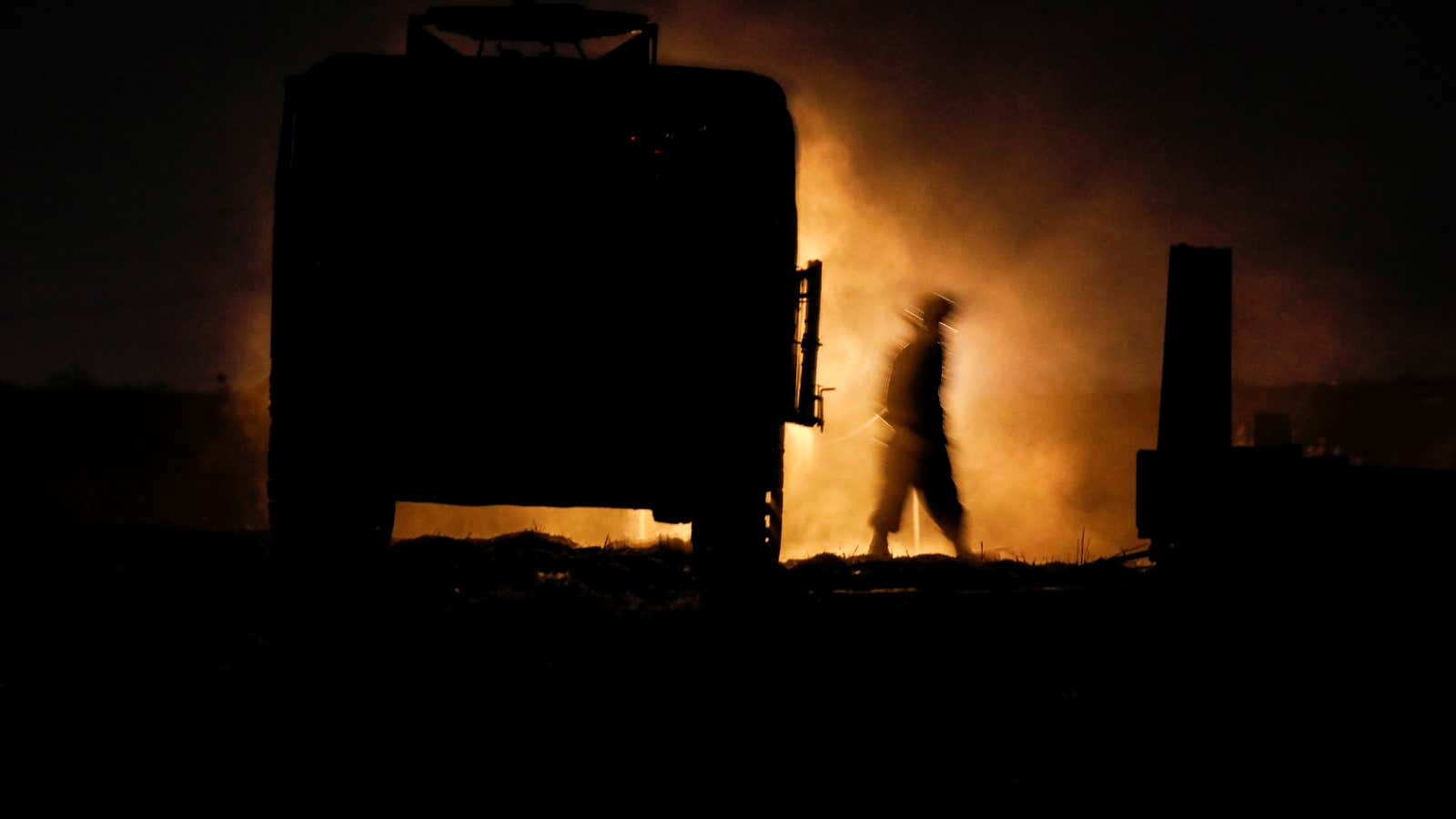 An Israeli soldier walks next to a military vehicle along the Israeli border with Gaza.