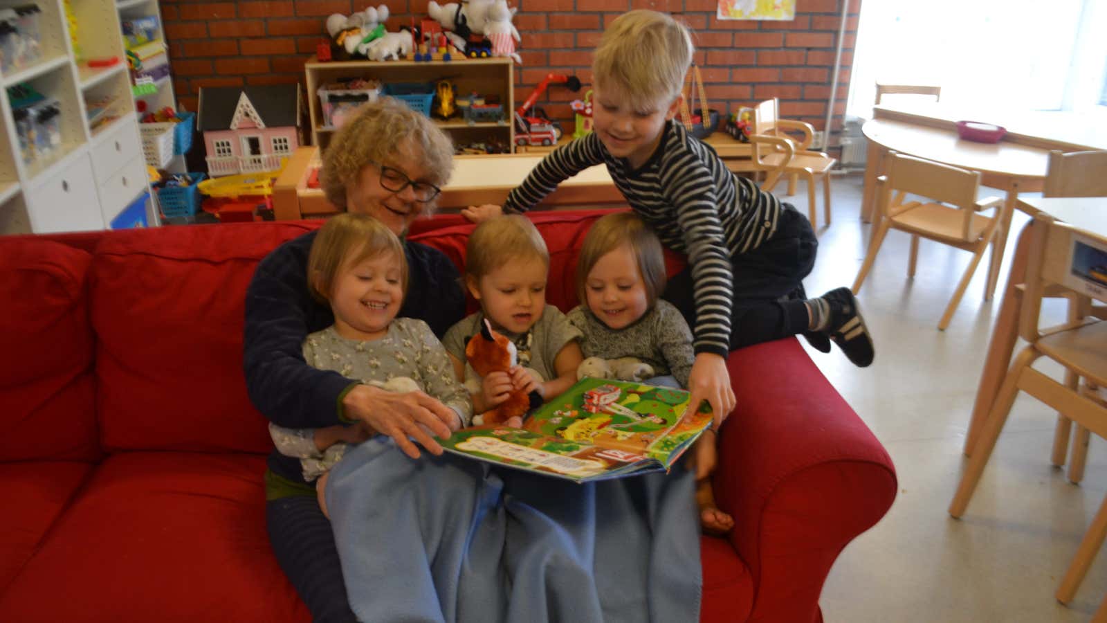 Communal grandmother Marjatta Ahonen reads a book to children at the Tammi nursery in Helsinki, Finland.
