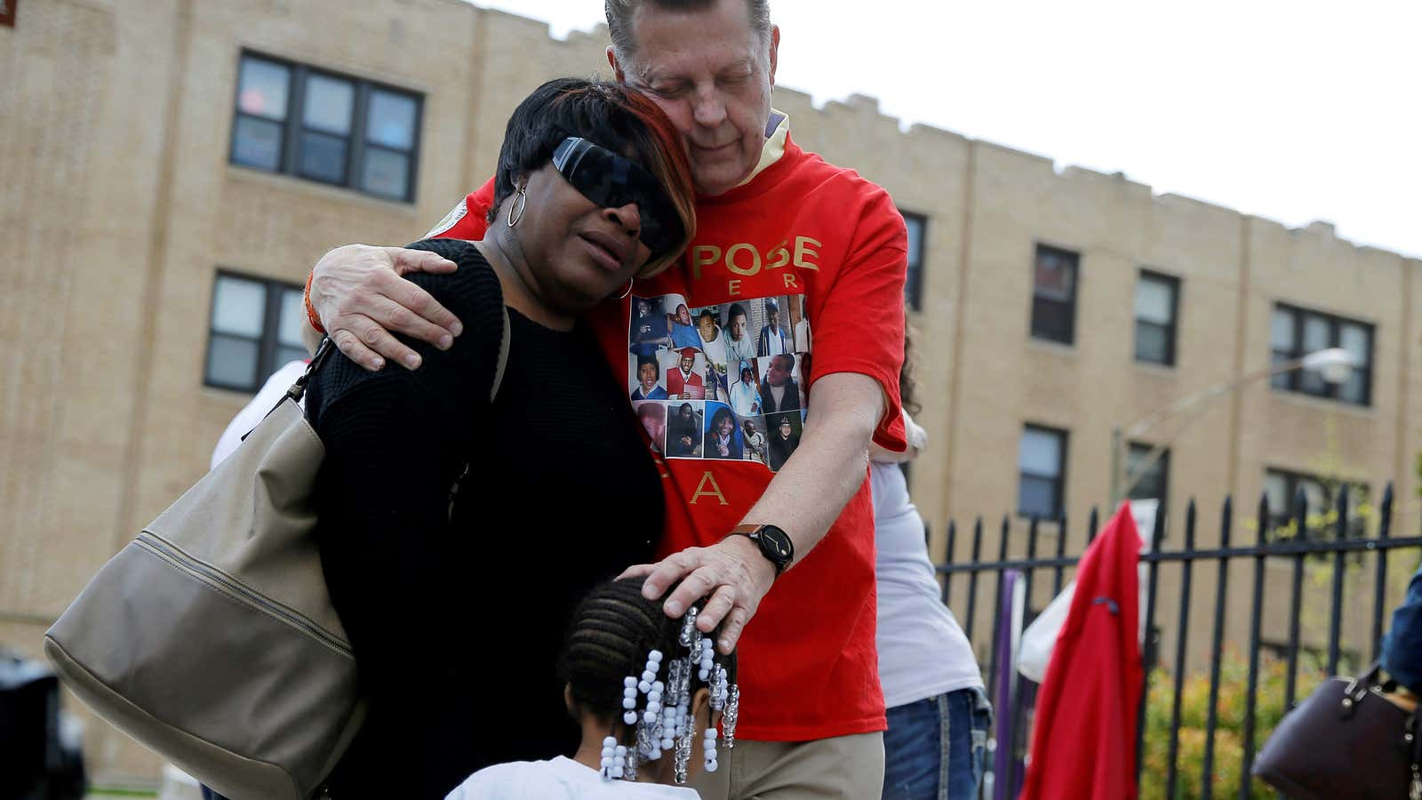 Father Michael Pfleger comforts family members of a gun violence victim.